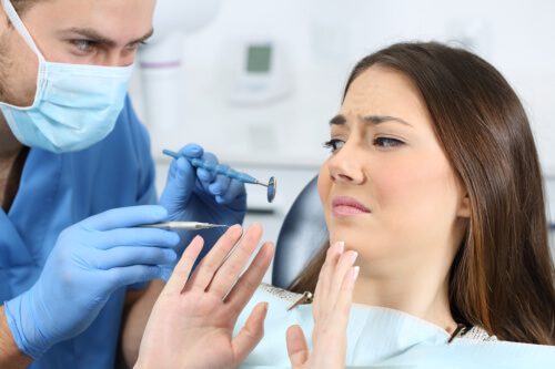En kvinde sidder i en tandlægestol og virker utilpas overfor situationen
